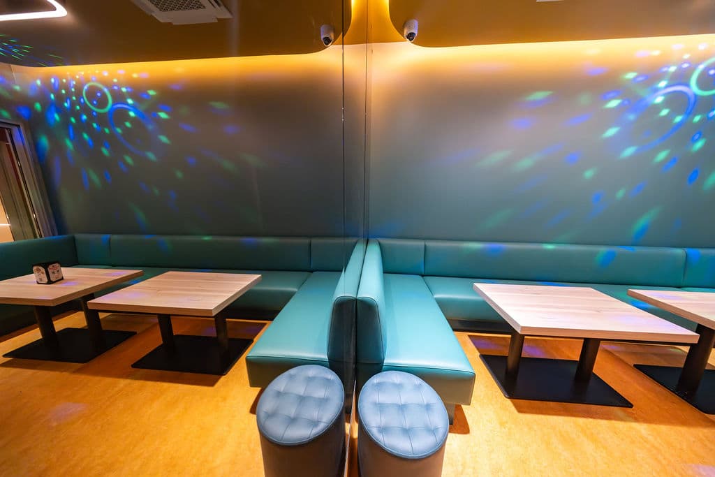 Teal booth seating washed in blue and green disco-ball light