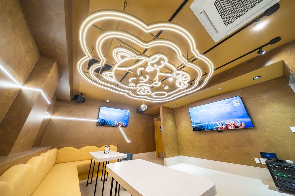 VIP karaoke room with two wall-mounted screens beneath the Manecky ceiling light