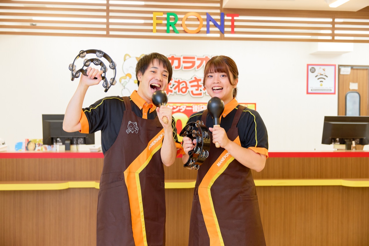 Two Manekineko staff cheering with a tambourine and maracas